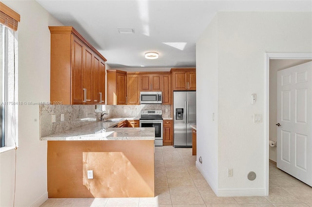 5220 SW 139th Ter, Miramar, FL 33027 - kitchen with appliances with stainless steel finishes, light tile patterned flooring, decorative backsplash, brown cabinetry, and a peninsula