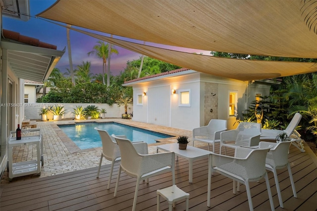 pool at dusk with a deck, a fenced in pool, and a fenced backyard