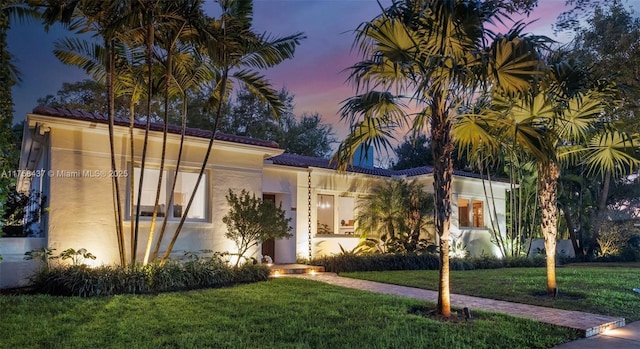 mediterranean / spanish home with stucco siding and a yard