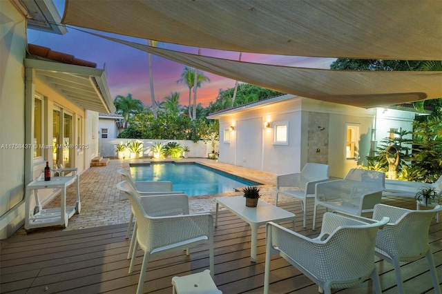 pool at dusk featuring a fenced in pool, a fenced backyard, and a wooden deck