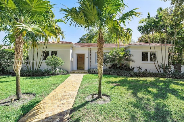 mediterranean / spanish-style home featuring a tiled roof, a front yard, and stucco siding