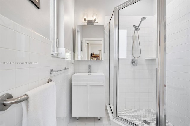 bathroom with a stall shower, tile walls, and vanity