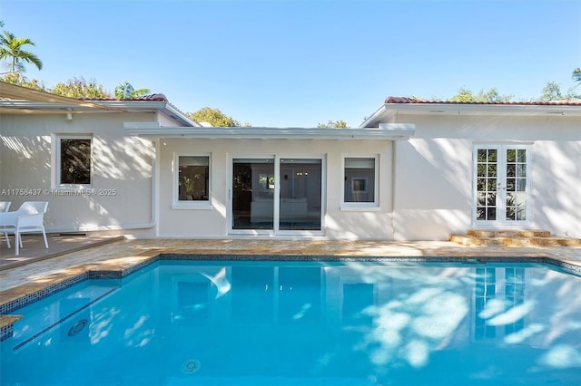 back of house with an outdoor pool and stucco siding