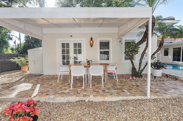 view of patio featuring an outbuilding, french doors, fence, and a storage unit