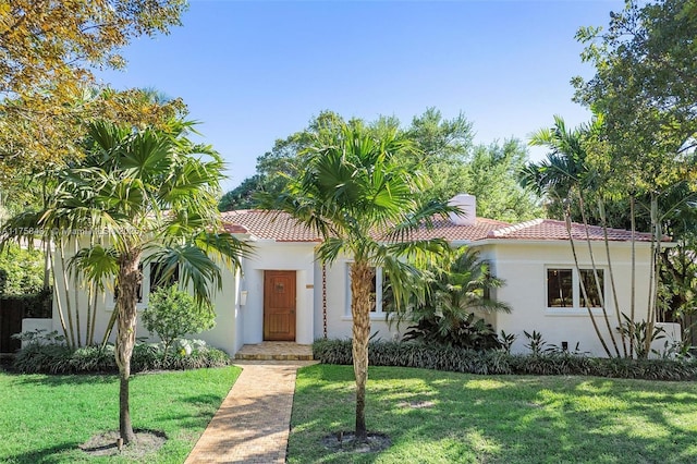 mediterranean / spanish-style home featuring a tile roof, a front lawn, and stucco siding