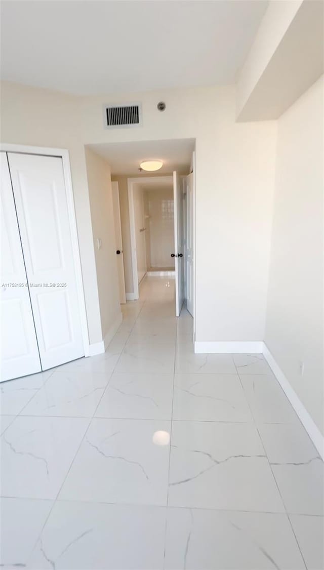 hallway with visible vents, marble finish floor, and baseboards