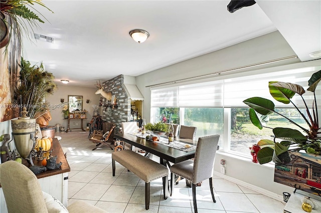 dining space featuring baseboards, a fireplace, visible vents, and light tile patterned flooring