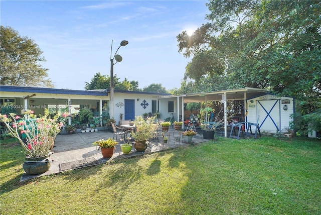 back of house featuring a yard, an outdoor structure, a patio, and a storage shed