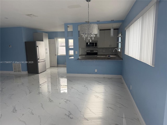 kitchen featuring stainless steel appliances, dark countertops, visible vents, and decorative backsplash