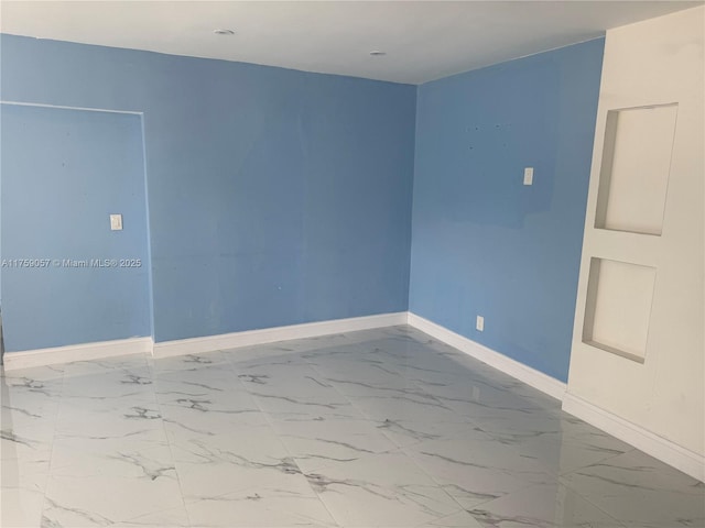 empty room featuring marble finish floor and baseboards