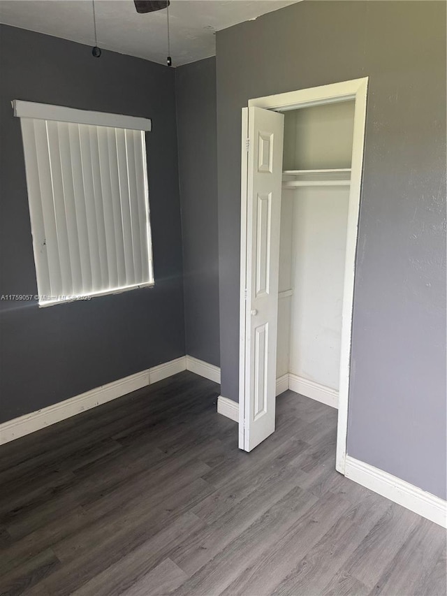 unfurnished bedroom featuring a closet, wood finished floors, and baseboards