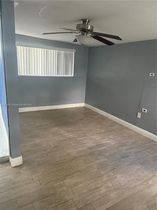 empty room with ceiling fan, baseboards, and wood finished floors