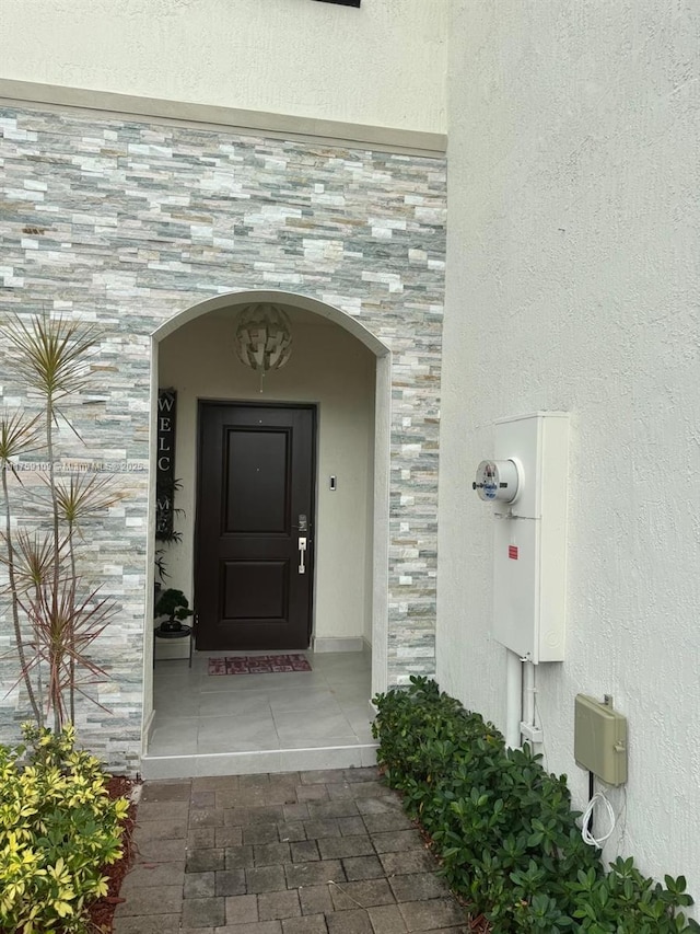 view of exterior entry featuring stone siding and stucco siding