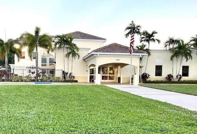 back of property with a tiled roof, a lawn, fence, and stucco siding