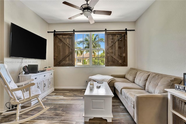 living room with dark wood-type flooring, ceiling fan, baseboards, and a barn door