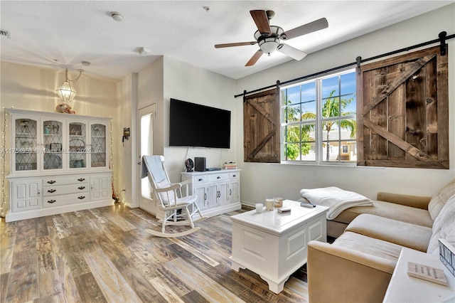 living area featuring a barn door, visible vents, ceiling fan, and wood finished floors