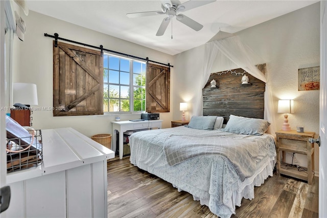 bedroom featuring a barn door, ceiling fan, and wood finished floors