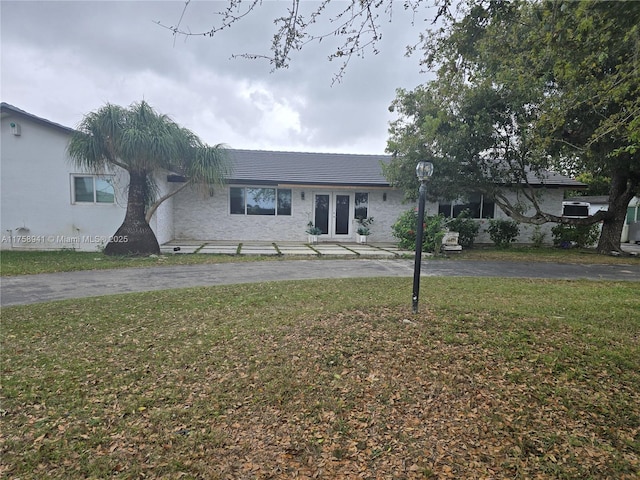 ranch-style house with driveway, french doors, and a front yard