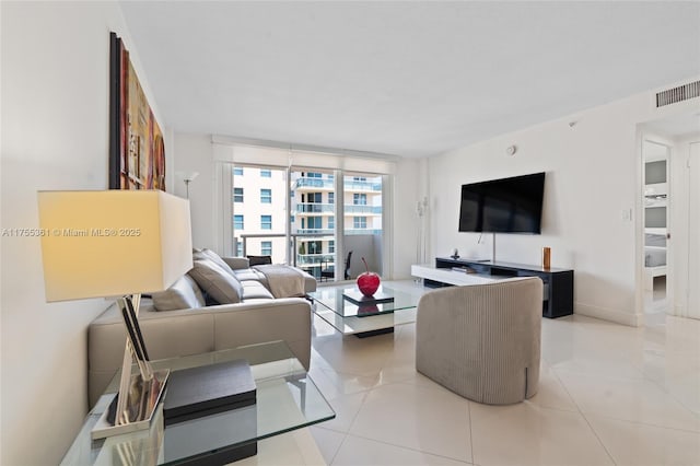 living area featuring light tile patterned floors, visible vents, and baseboards