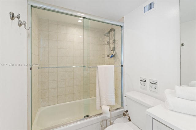 bathroom featuring visible vents, vanity, toilet, and bath / shower combo with glass door