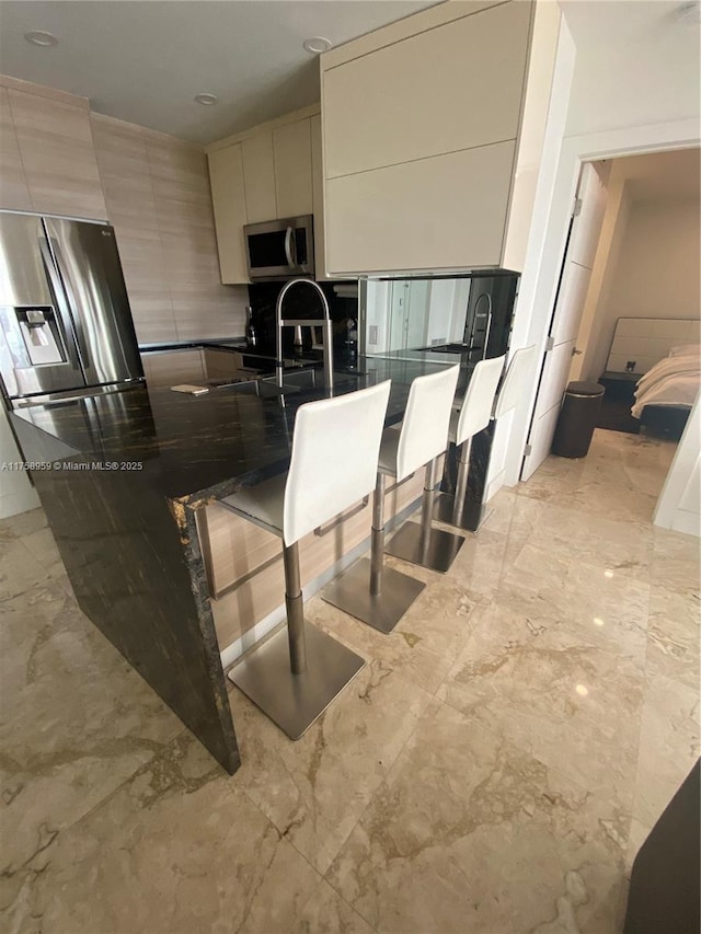 kitchen with marble finish floor, appliances with stainless steel finishes, a sink, modern cabinets, and a peninsula