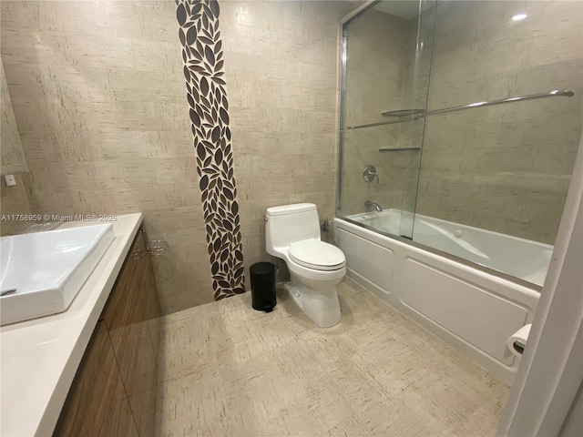 bathroom with combined bath / shower with glass door, vanity, and toilet