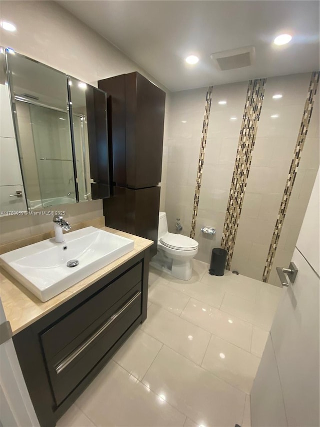 bathroom featuring visible vents, toilet, a shower with door, tile patterned floors, and vanity