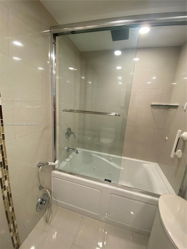 full bathroom with a combined bath / shower with jetted tub, toilet, and tile patterned floors