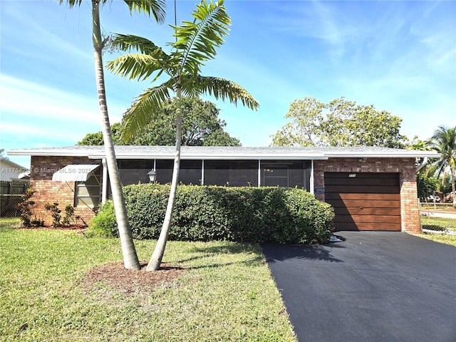 view of front of house featuring a garage, a front lawn, aphalt driveway, and brick siding