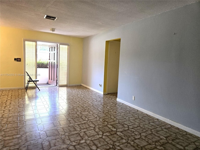 spare room with visible vents, a textured ceiling, and baseboards