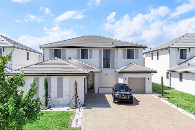 view of front of house with a tiled roof, stucco siding, decorative driveway, and a garage