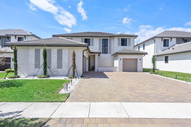 view of front of house with a garage, a front lawn, decorative driveway, and stucco siding