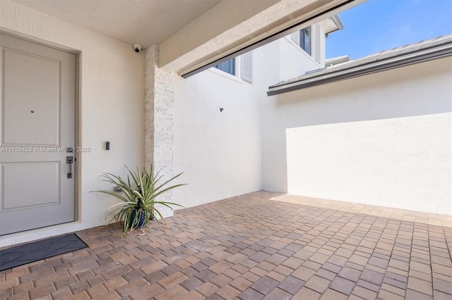 view of exterior entry featuring stucco siding and a patio area