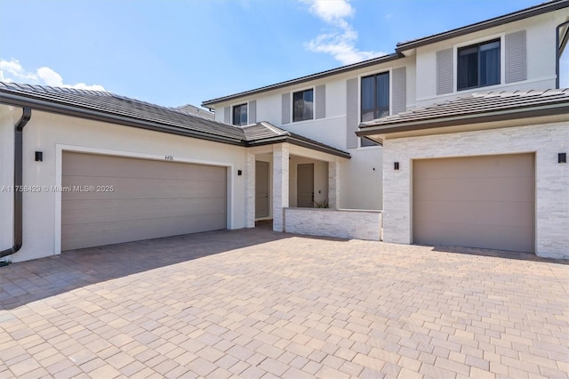 view of front of home with a tile roof, decorative driveway, and stucco siding