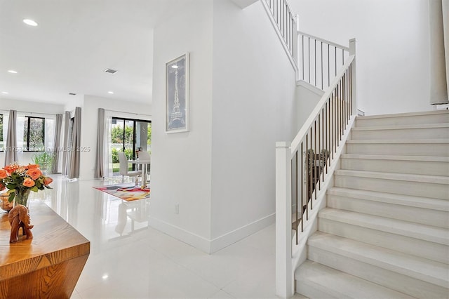 staircase featuring baseboards, tile patterned floors, and recessed lighting