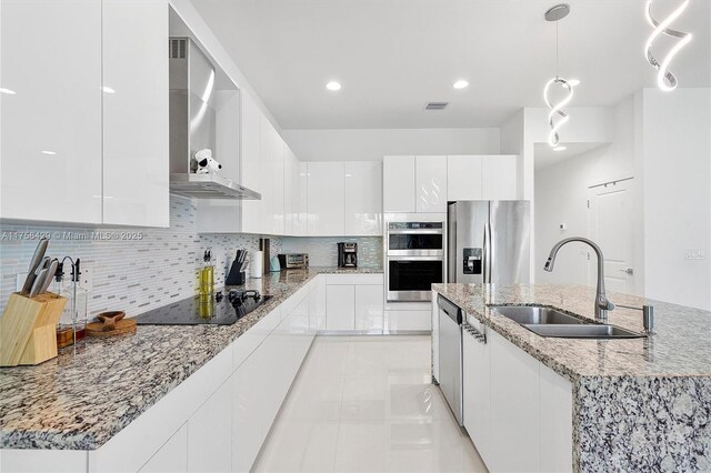 kitchen with a sink, wall chimney exhaust hood, appliances with stainless steel finishes, modern cabinets, and visible vents