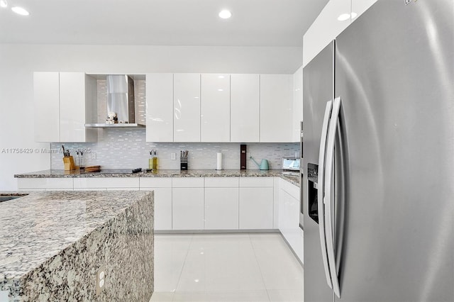 kitchen with wall chimney exhaust hood, stainless steel refrigerator with ice dispenser, light tile patterned floors, and tasteful backsplash