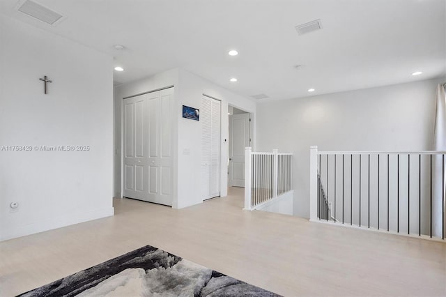 empty room with baseboards, wood finished floors, visible vents, and recessed lighting