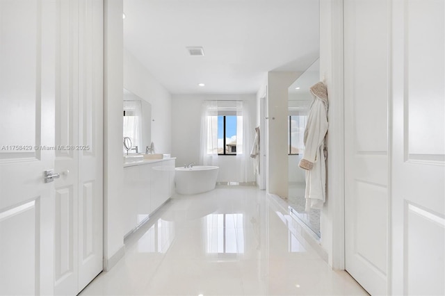full bath with visible vents, a freestanding tub, and vanity
