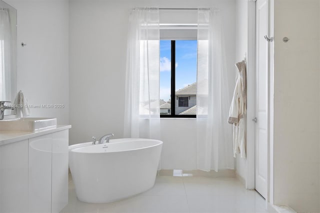 full bathroom featuring a freestanding tub, vanity, and tile patterned floors