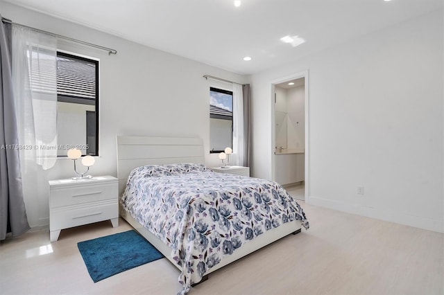 bedroom featuring ensuite bath and baseboards