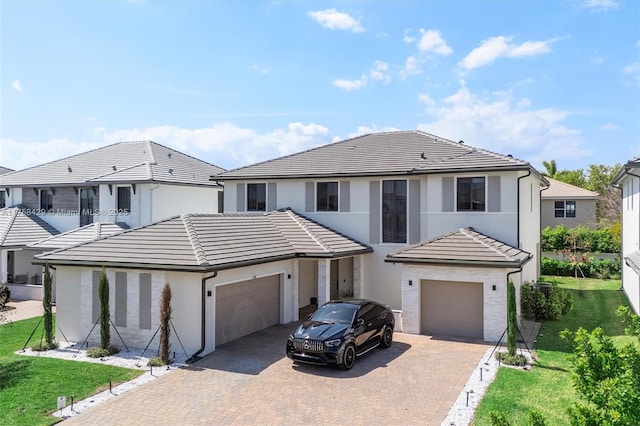 view of front facade with a tiled roof, decorative driveway, stucco siding, and an attached garage