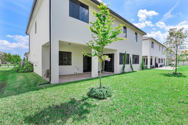 back of property with stucco siding, a yard, and a patio area