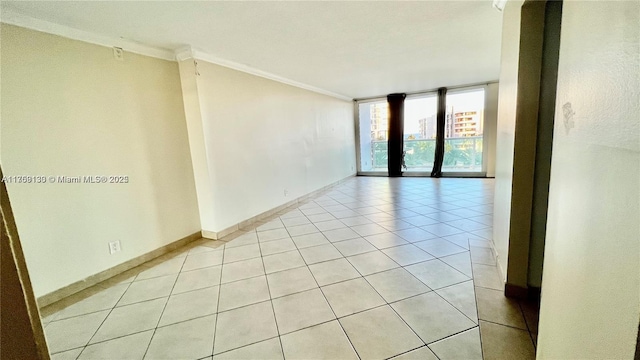 spare room featuring baseboards, expansive windows, ornamental molding, and light tile patterned flooring