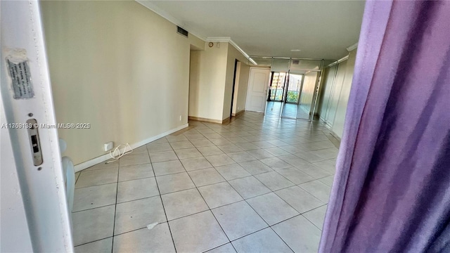 hall with baseboards, visible vents, crown molding, and light tile patterned flooring