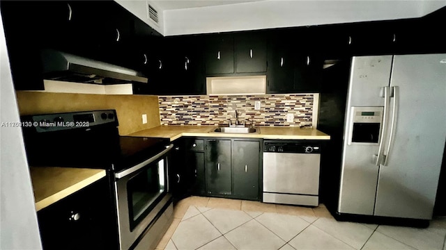 kitchen featuring a sink, appliances with stainless steel finishes, light countertops, and dark cabinets