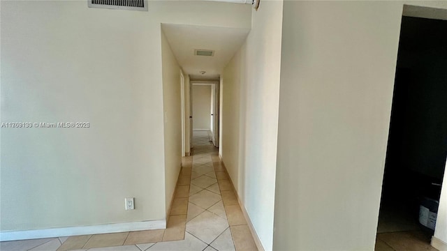 corridor with visible vents, baseboards, and light tile patterned floors