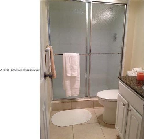 full bath featuring toilet, a shower stall, vanity, and tile patterned floors