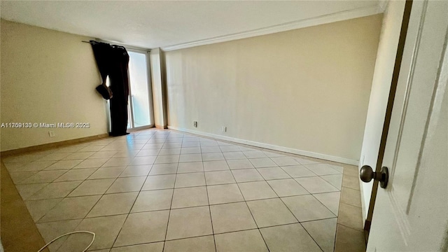 spare room featuring light tile patterned flooring, crown molding, and baseboards