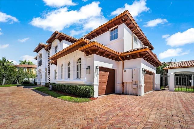 view of front of home with decorative driveway, an attached garage, and stucco siding